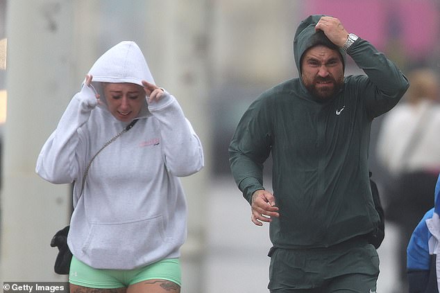A family fights against the wind as they walk down Blackpool Promenade