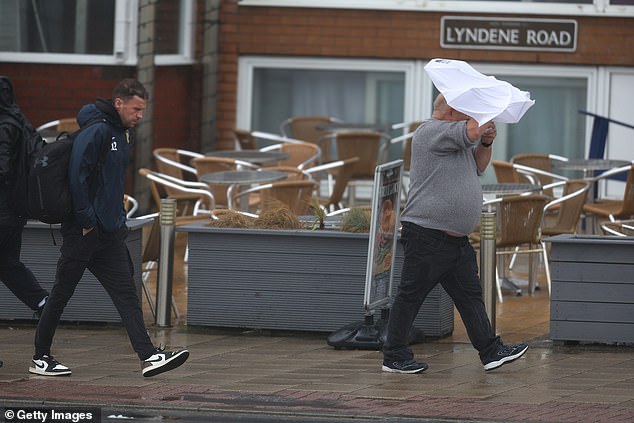 A man fights with his umbrella in the strong winds as he walks along Blackpool Promenade
