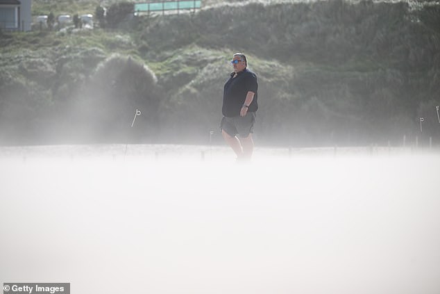 A man stands as wind blows sand across the beach in Portstewart in Northern Ireland
