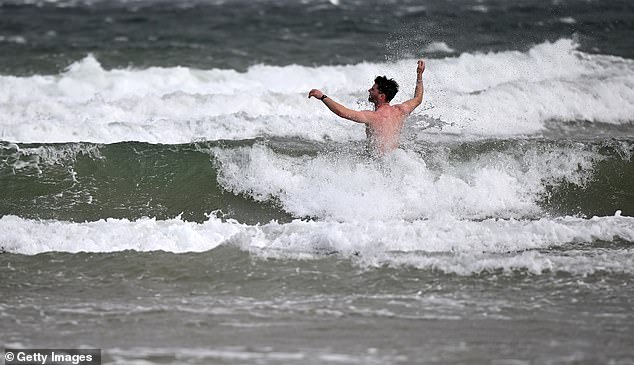 A man battles the wind and the waves in the sea on Portstewart Strand in Northern Ireland