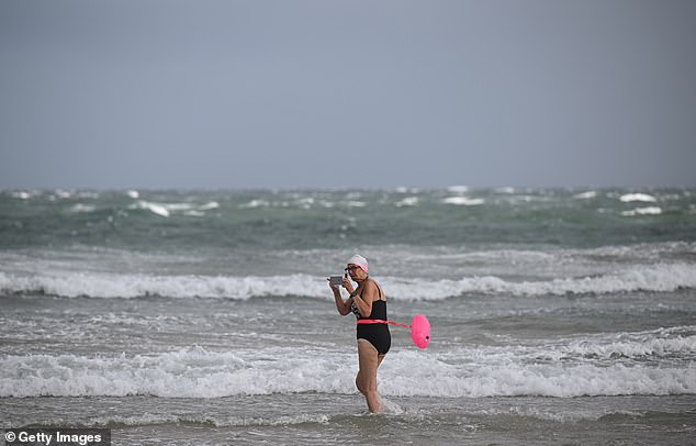 A lady battles the difficult weather to go for a swim in Northern Ireland accompanied by a pink float