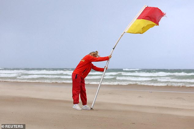 A lifeguard struggles to erect a flag in the high winds on a beach in Northern Ireland
