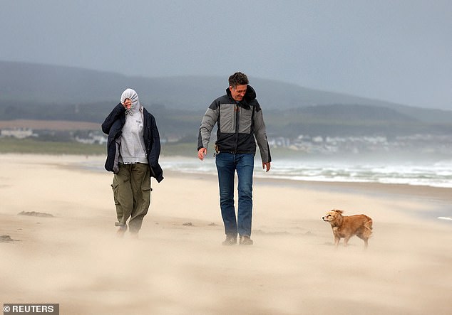 People walk their dog during Storm Floris on the north coast of Northern Ireland in the storm