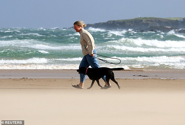 A person walks their dog during Storm Floris on the north coast of Northern Ireland, Portstewart