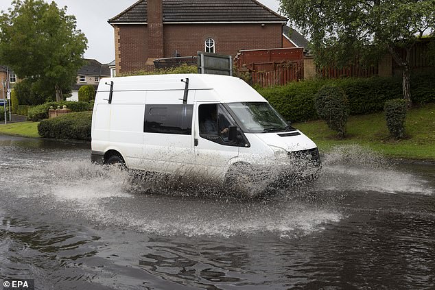A vehicle drives through localised flooding in the East End of Glasgow, Scotland