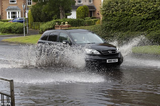 A vehicle drives through localised flooding in the East End of Glasgow, Scotland
