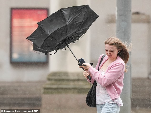A woman has her umbrella blown inside out due to strong winds in Manchester