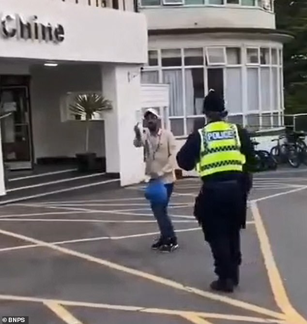 An asylum seeker was filmed giving the finger to protesters outside a migrant hotel in Dorset before being ushered away by police