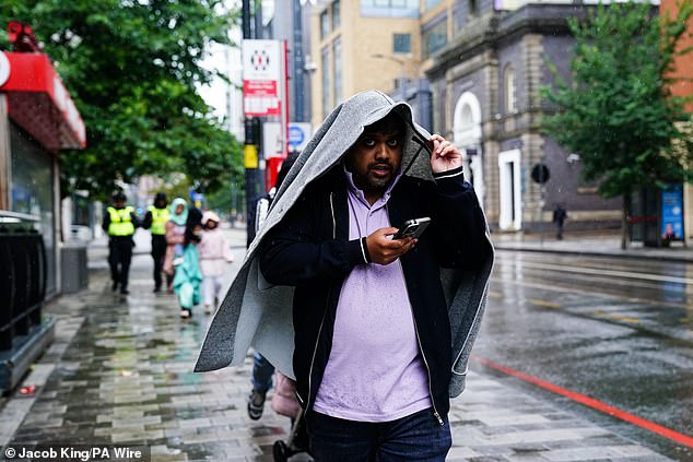 A man uses a coat to cover themselves from rainfall in Birmingham as Storm Floris hits