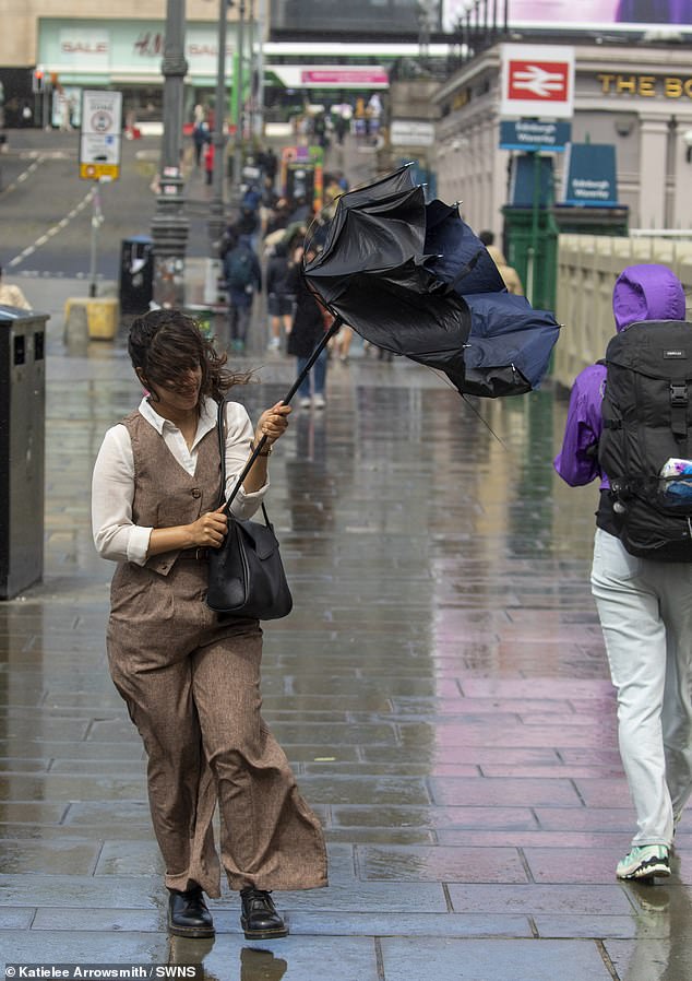 A woman battles with an umbrella on the streets of Edinburgh in the wind and the rain