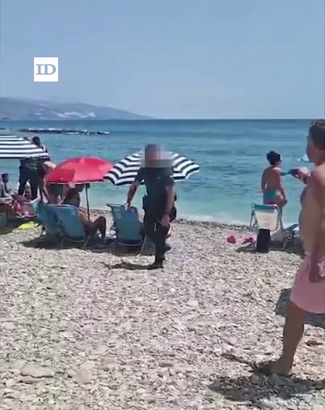 The occupants of the boat dove into the water in front of stunned holidaying families. Pictured: A police officer is seen walking on the beach following the incident