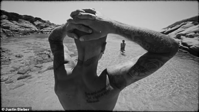 Justin watches as his wife plays with their child in the water