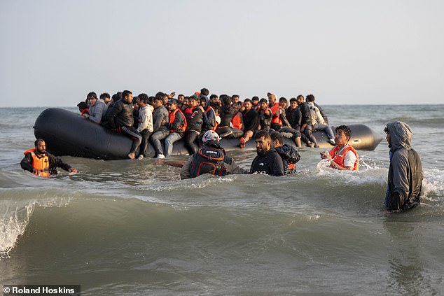 The groups of migrants spread over a mile of shoreline, gathering in three bunches, with one bunch stood a little back on the beach, and the other two groups in the water up to their waists