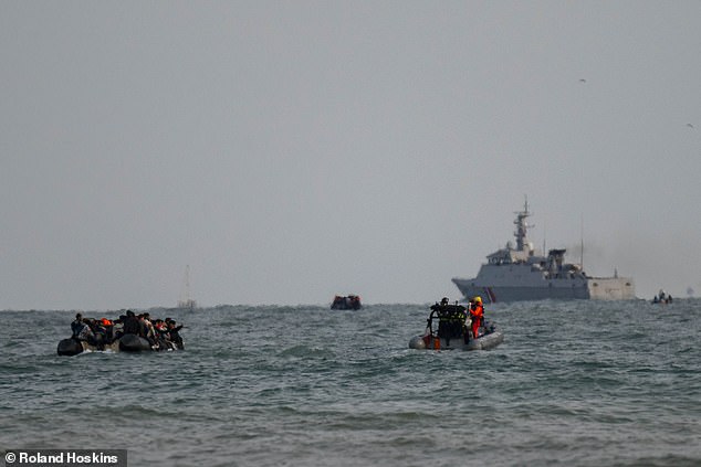 A boat packed with migrants is seen sailing away from Gravelines beach today