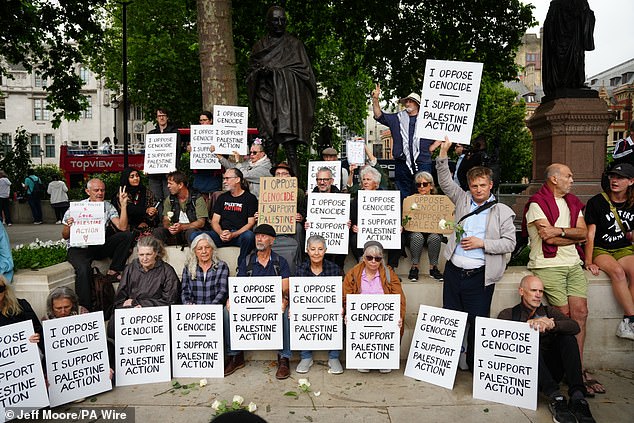 People take part in a protest in support of Palestine Action, organised by the Defend Our Juries group, in front of the Mahatma Gandhii statue in Parliament Square