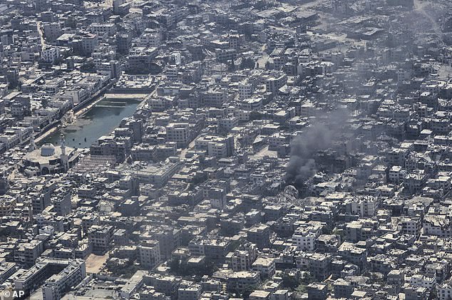 From aboard a Jordanian Air Force C-130, smoke is seen rising from Gaza City during an aid airdrop, Thursday, Aug. 7, 2025