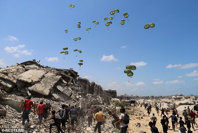 Pictured: Palestinians run towards parachutes carrying aid packages airdropped over northern Gaza Strip