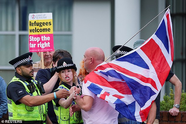 Police scuffle with an anti-immigration demonstrator outside the Cresta Court hotel, in Altrincham