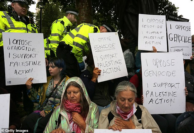 Police are gearing up to make mass arrests on Saturday when more than 500 people are expected to descend on London in solidarity with the outlawed pro-Gaza group. Pictured: Supporters of Palestine Action hold up signs at a rally in July