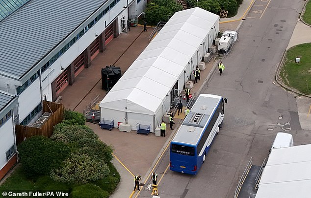 People thought to be migrants disembark a coach at the Manston Immigration Processing Centre in Manston, Kent, following a small boat incident in the Channel on August 7, 2025