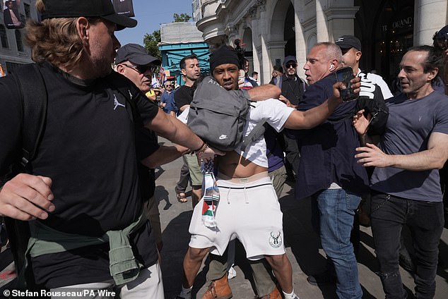 A pro-Palestinian supporter (centre, in white) is removed after interrupting the rally