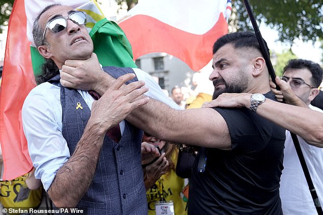 A man (left) taking part in the march is grabbed by the throat by another man, who was detained by police following the incident, during the National March For The Hostages, in central London