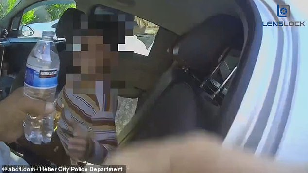 The officer is seen handing the hot child water after he rescued him from the car
