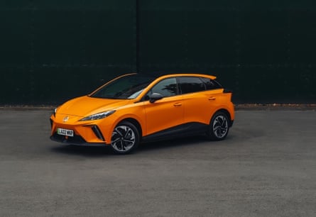 An orange MG4 car pictured in front of a dark background