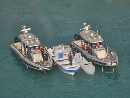 A low-profile unmanned semi-submersible vessel sits between two Colombian Navy boats off the coast of Tayrona Park near Santa Marta, Colombia