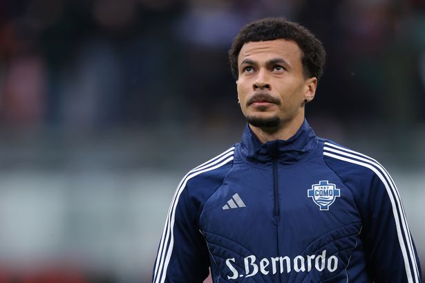 Dele Alli in a Como football club jacket on a pitch.