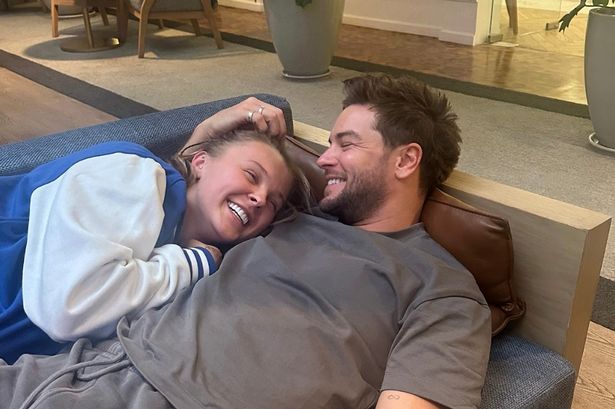 JoJo Siwa and Chris Hughes cosied up together on a sofa.