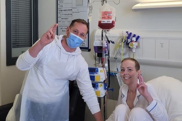 Natalie Forrest and John Forrest pose for a photo from a hospital bed 