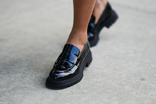 A shot of someone's feet wearing loafers and walking on pavement