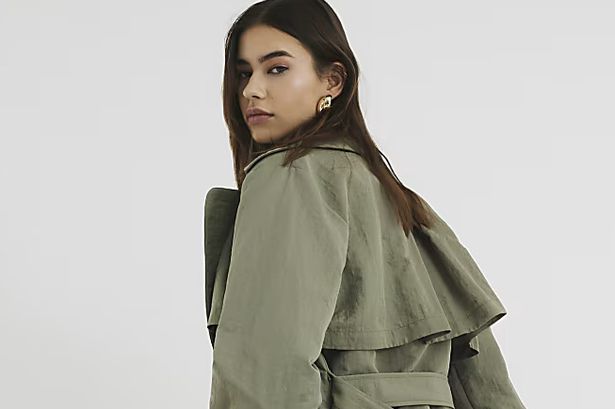Model wears khaki trench with matching trousers and heels