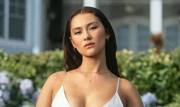 A woman in a white dress looks serious