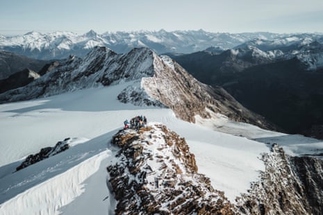 A group of hikers on a snowy mountain ridge with views all around