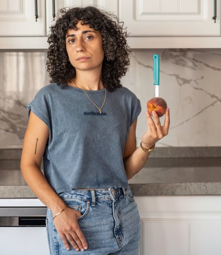 Trickshot star Gamze May, holding a piece of fruit with a knife in it
