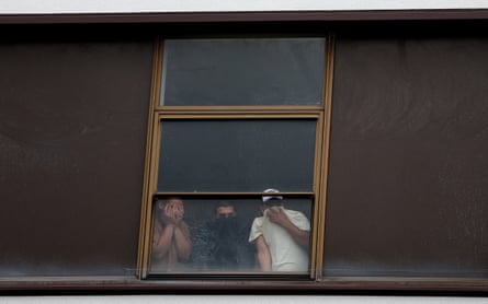 People cover their faces as they look out of a window of the Barbican Thistle hotel in London.