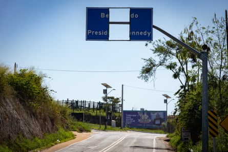A broken overhead road sign that says: ‘Presid … nnedy’