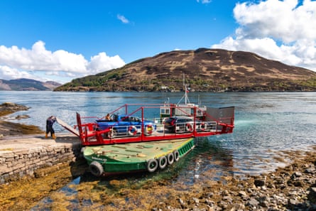 A small ferry at a sloping pier, with a turntable on it holding two cars 