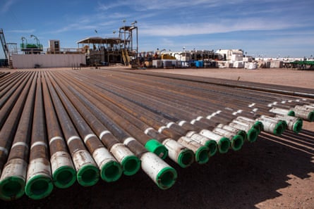 A line of pipes lies in front of mining infrastructure.