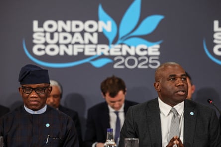 A group of men sitting in front of a sign saying London Sudan conference