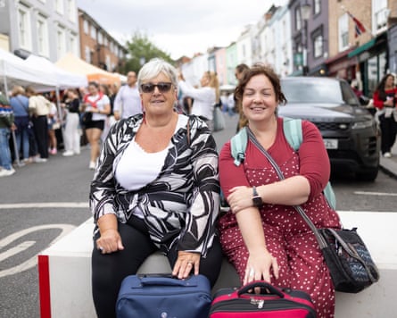 Twiggs smiles at the camera while sitting on a barrier at the market next to her mother
