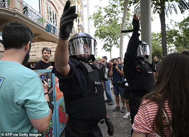 Anti-riot forces gesture as protestors marched through Barcelona's Las Ramblas alley, on July 6