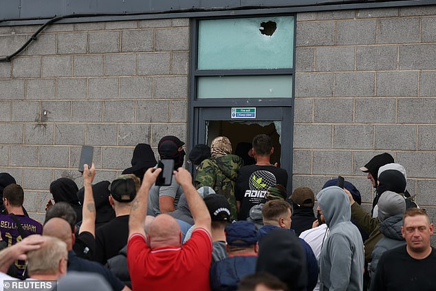 Protesters try to cram into the migrant hotel through a damaged fire exit in Rotherham