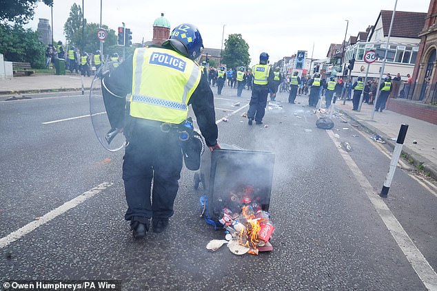 A police officer moves a burning bin in Middlesbrough
