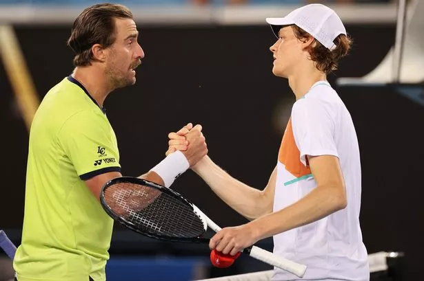 Italy's Jannik Sinner (R) shakes hands with Steve Johnson of the US after their men's singles match on day four of the Australian Open tennis tournament in Melbourne on January 20, 2022.