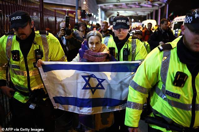 Police officers escort a woman with an Israeli flag away from Pro-Palestinian protesters outside Villa Park