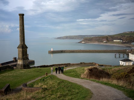 A group of boys walk down a coastal path towards a harbour