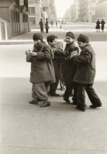 a black and white photo of 7 young boys walking along smiling and laughing in an urban city street